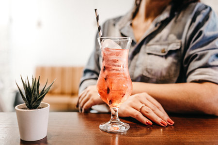 A closeup shot of a female drinking a cold strawberry cocktail in a cafeの写真素材