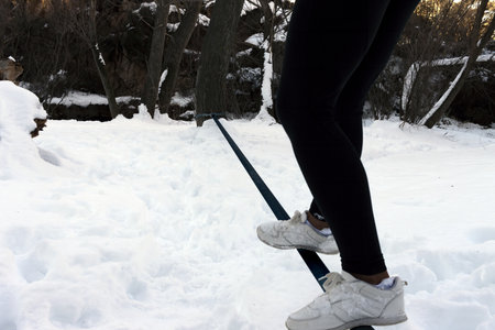 A person whose only legs are visible balances on a tightrope in the snowの写真素材
