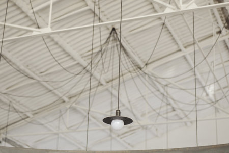 A low angle shot of a decorative lamp hanging from a ceiling with wiresの写真素材