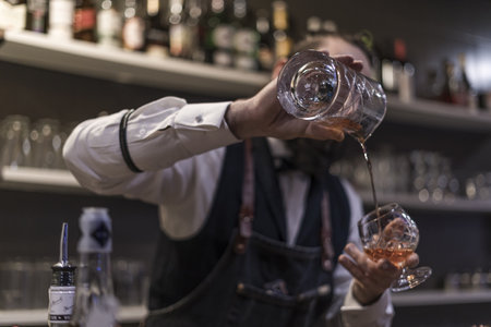 A bartender making an alcoholic drink with ice at the night clubの写真素材
