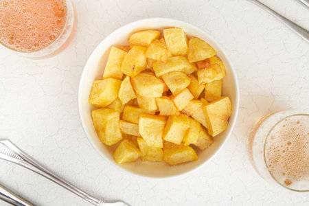 A high angle shot of chunks of potatoes in a bowl and glasses of drinkの写真素材