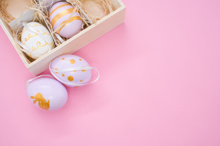 A top view of painted Easter eggs on a box with straw isolated on pink background with copy spaceの写真素材