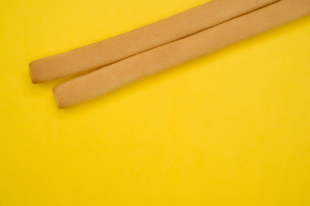 A closeup shot of two breadsticks isolated on yellow backgroundの写真素材