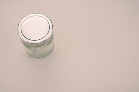 A top view of an empty glass jar with a silver lid isolated on gray backgroundの写真素材
