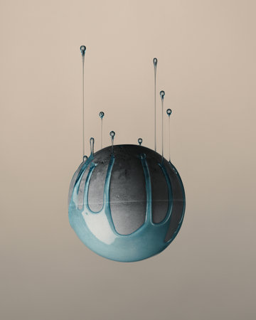 An upside-down of a gray ball with blue paint dripping upward isolated on pink background