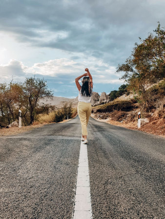A closeup view of a person standing on the empty highway on a sunny summer dayの写真素材