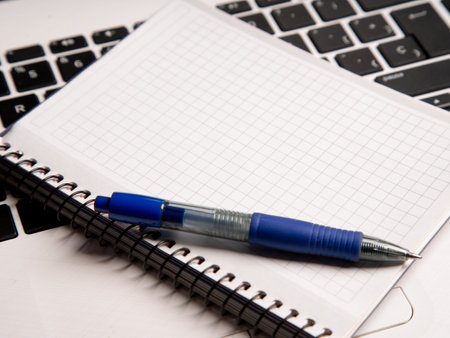 A high angle shot of a blank notebook and a pen on a laptopの写真素材