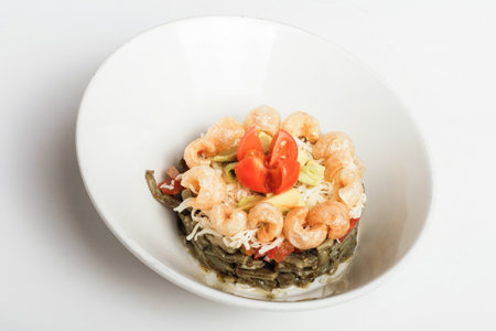 A delicious vegan salad with tomatoes, shrimps, and other ingredients on a white plateの写真素材
