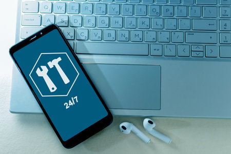 A top view of a smartphone with a 24/7 technical support app on a laptop on the table