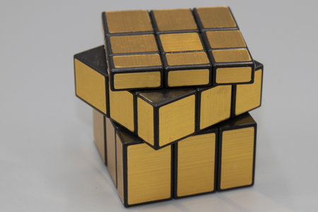 A closeup shot of a golden cube-shaped puzzle on a white surface
