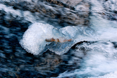 A selective focus shot of a frozen water stream in winter