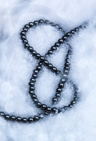 A top view of a necklace made of black beads in the snowの写真素材
