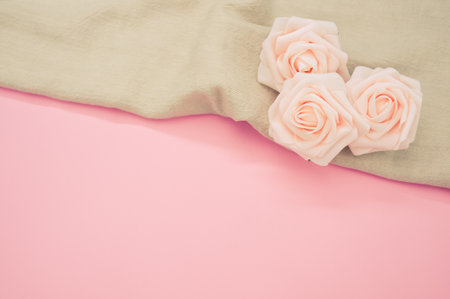 A closeup shot of a beige winter scarf with pink roses on a pink surface - copy spaceの写真素材
