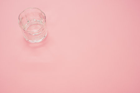 A closeup shot of an empty glass on a pink surface - copy spaceの写真素材
