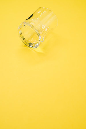 A closeup shot of an empty glass on a yellow surface - copy spaceの写真素材
