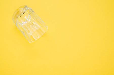 A closeup shot of an empty glass on a yellow surface - copy spaceの写真素材