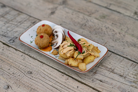 Fresh champignons, chicken cutlets and fried potatoes on a plate on a wooden tableの写真素材