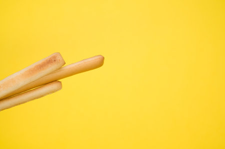 A closeup shot of breadsticks with copy space on a yellow background
