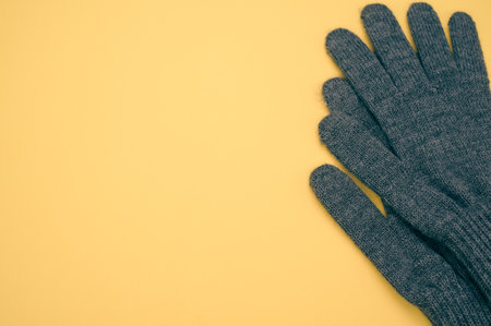 A closeup shot of gray knitted pair of gloves on a yellow backgroundの写真素材