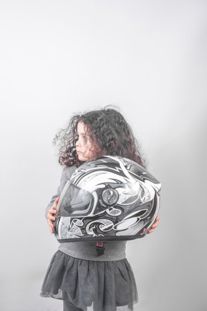 A beautiful caucasian curly hair girl holding on a gray helmet on a white background