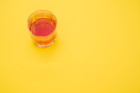 A closeup shot of a glass of whiskey on a yellow backgroundの写真素材