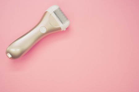 A top view of a golden epilator on a pastel pink surface for a copy spaceの写真素材