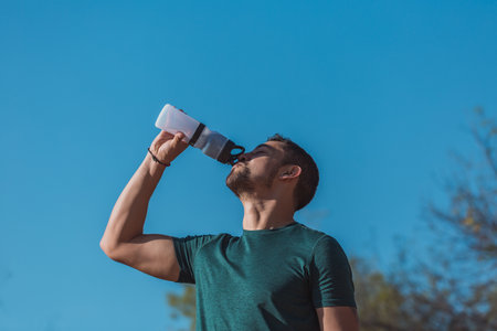 A closeup shot of Hispanic male drinking water after exercisingの写真素材