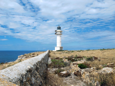 A beautiful view of lighthouse on a cliff under a cloudy sky in Formentera, Spainの写真素材