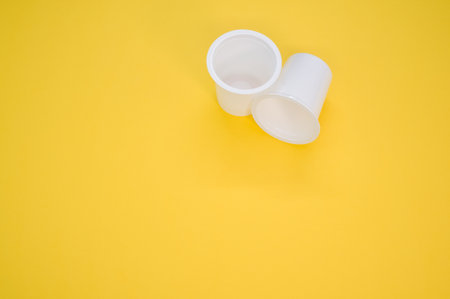 A top view of plastic white cups on a yellow surface for a copy spaceの写真素材