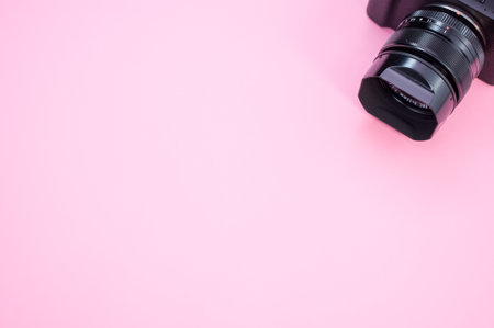 A closeup of a camera on a pastel pink surface for a copy space