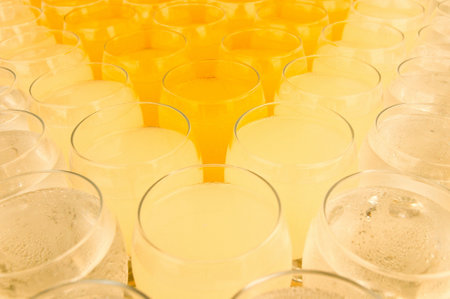 A closeup shot of orange and yellow drinks on wine glassesの写真素材