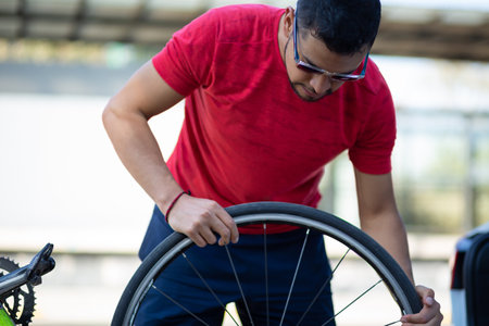 A closeup shot of  Hispanic man fixing his bikeの写真素材