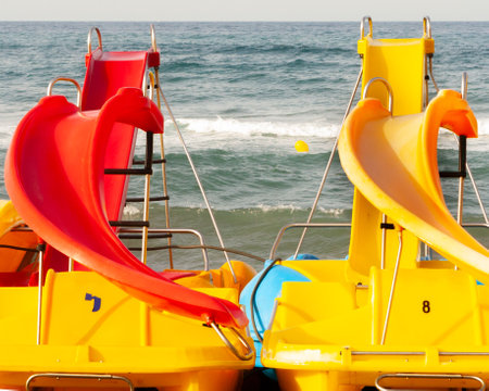 A Funny scene on a summer day on the sunny beach with yellow and red pedal boats.の写真素材