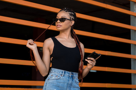 A cool young Afro-American lady with deadlocks standing in front of an orange construction