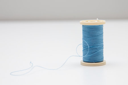 A spool of light blue thread for sewing; a light background with a copy space