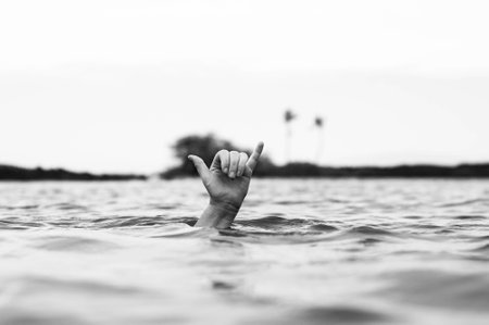 A grayscale shot of a hand on the surface of a lake showing a Decompression sign for diversの写真素材
