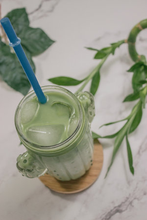 A vertical shot of a crystal glass full of yummy matcha tea mixed with honey and sugarの写真素材