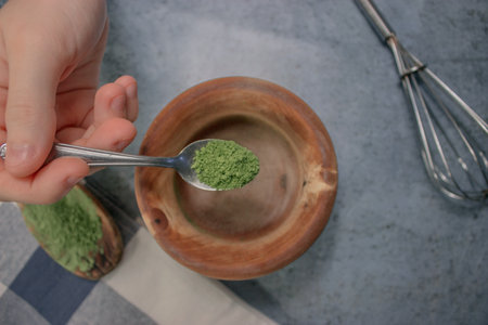 A top view of a person adding green matcha tea powder in a bowlの写真素材