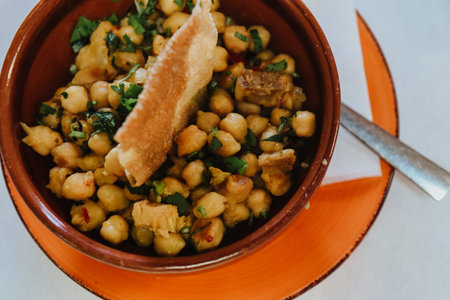A high angle shot of a bowl of a delicious dish with chickpeas and spices on the table