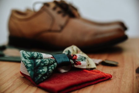 A closeup shot of a colorful bow tie on a red handkerchief with brown shoes in the backgroundの写真素材