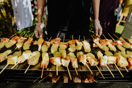 A closeup shot of a cook preparing meat and pineapple slices on skewers onの写真素材