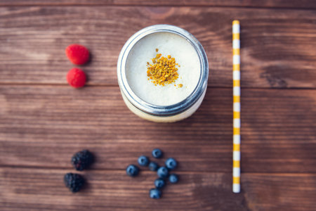 A top view of a glass of smoothie with berries and straw on wooden backgroundの写真素材