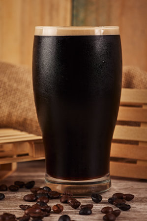 A vertical shot of a black beer in a glass with coffee beans