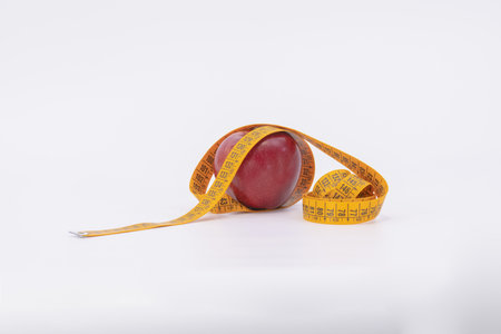 red apple with measure tape as symbol for diet and weight control