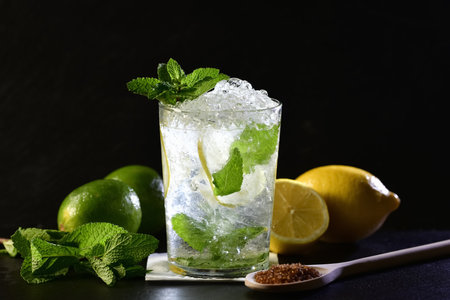 Selective focus and close up of a mojito cocktail with mint leaves, limes, lemons and a wooden spoon...