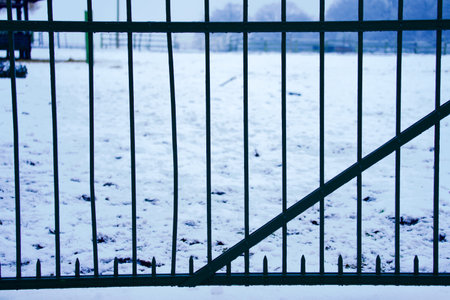 A closeup shot of a fence in front of a snowy field in winterの写真素材