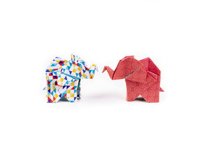 A closeup shot of two colorful patterned origami elephants standing face-to-face on a white backgroundの写真素材