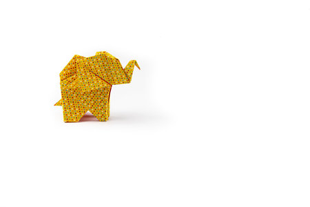 A closeup shot of a yellow patterned origami elephant isolated on a white backgroundの写真素材