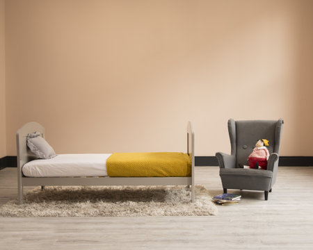 A wooden bed, an armchair and a toy in a child roomの写真素材