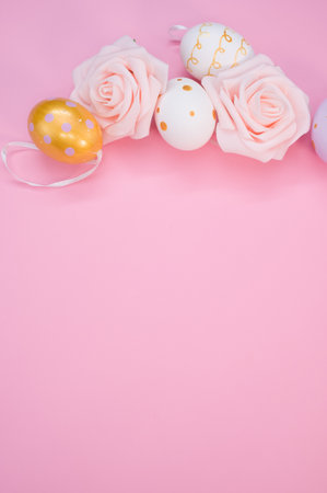 A vertical shot of cute decorative eggs for Easter and roses isolated on a pink backgroundの写真素材